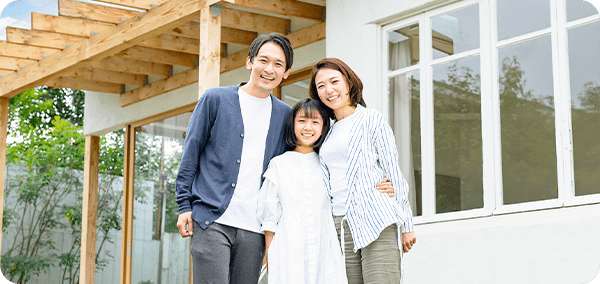 家の前で写真を撮影する3人家族